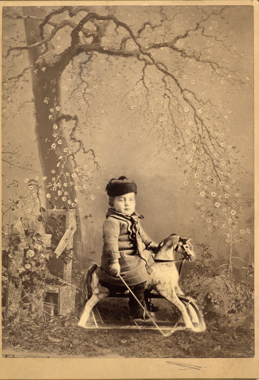 Jonge jongen zittend op een hobbelpaard met groot geschilderd decor, 1880s door American Photographer