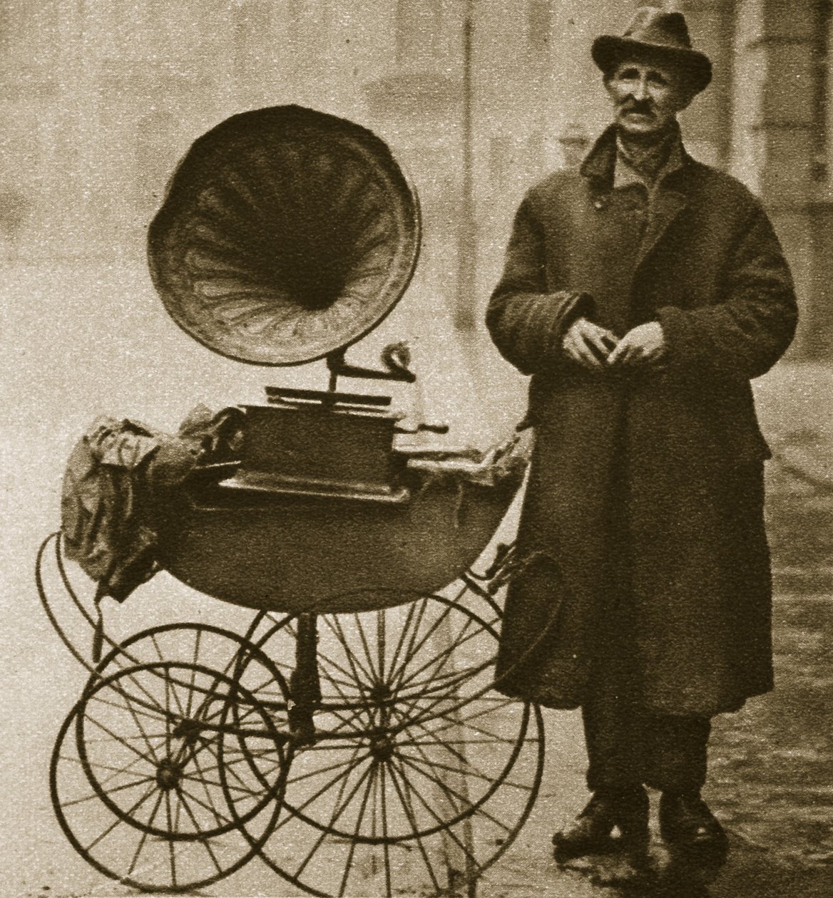 Een straatverkoper vermaakt met een grammofoon, vervoerd in een kinderwagen door English Photographer