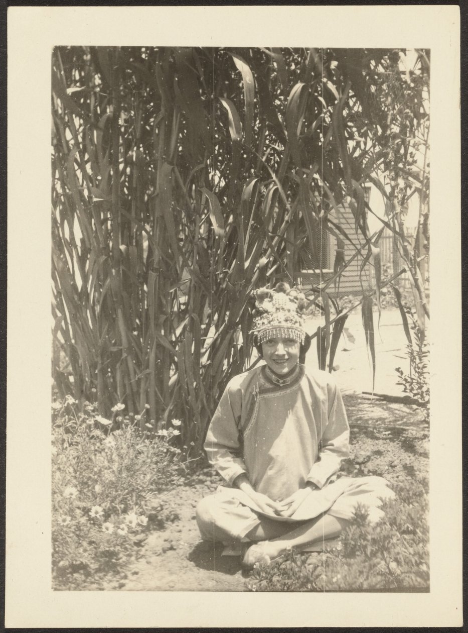 [Vrouw in kostuum zittend in tuin]. door Louis Fleckenstein
