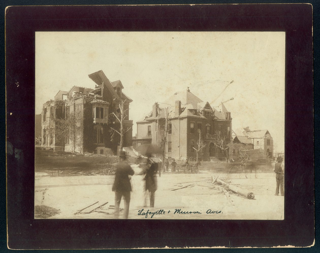 Horizontale, sepia foto van drie gedeeltelijk verwoeste huizen, ontbladerde bomen en toeschouwers die naar de schade door een tornado kijken door Unbekannt Unbekannt